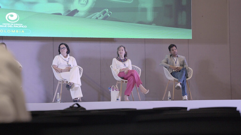 Tres conferencistas sentados en el escenario durante un panel.